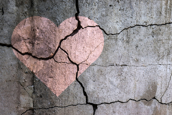 A pink heart shape is superimposed on a cracked concrete wall, with the cracks running through the heart—perfect imagery for a Good Grief blog post about healing and spiritual care.
