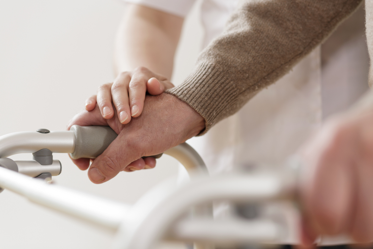 Close-up of a person’s hand on a walker, with another hand gently resting on top, symbolizing assistance or support—an image reflecting the essence of spiritual care and the reassurance found in leaning on God.